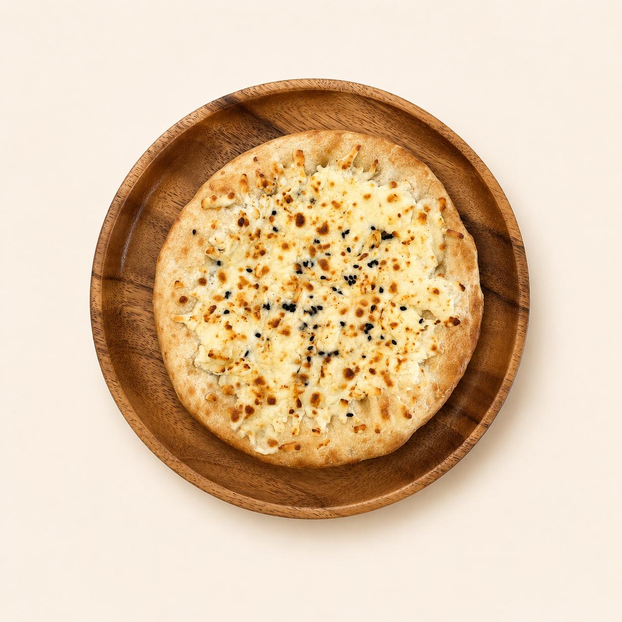 ivry.'s signature Ivry Cheese Blend flatbread on a wooden plate — warm flatbread topped with melted cheese and black sesame.